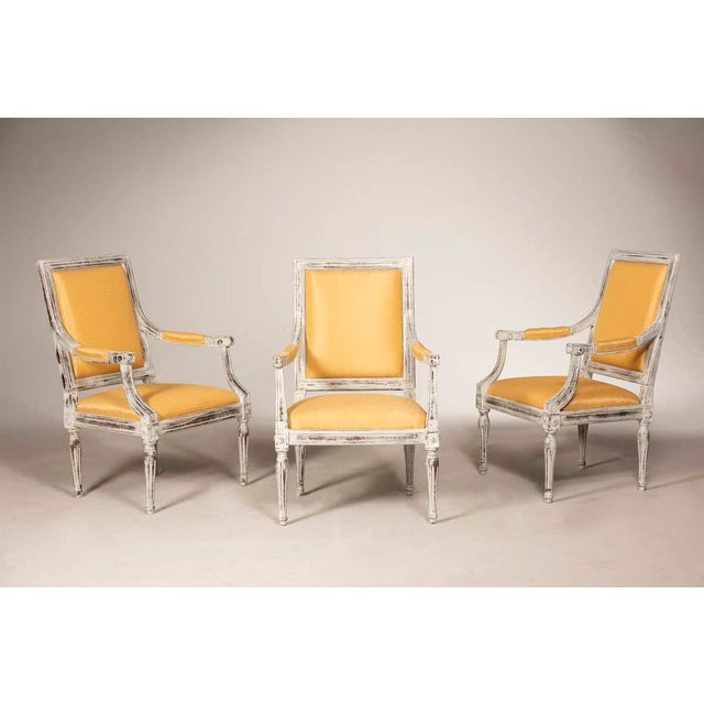 Three Louis XVI-style armchairs crafted in walnut wood, of Italian origin. The chairs have been distressed and carefully...