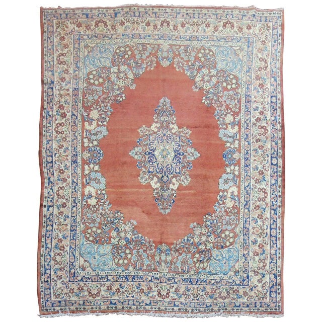 An authentic Persian Sarouk rug with a classic blue center medallion on an open field with a camel border. Accents of soft...