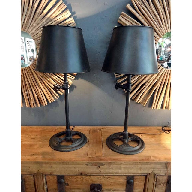 This industrial iron table lamp combines substantial cast-iron construction with sculptural form and beautifully aged...