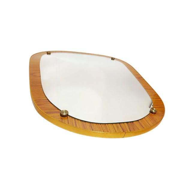 A vintage wall mirror, probably dating from the 1960s or 1970s, mounted on an organically shaped wood-veneered panel with...