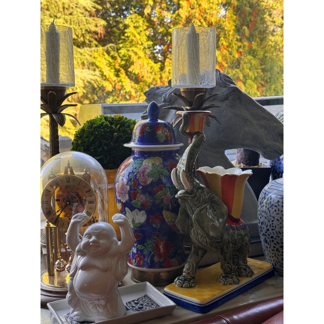 Presenting an auspicious elephant in celadon green holding an orange and yellow candle bobeche in its upright trunk. The...