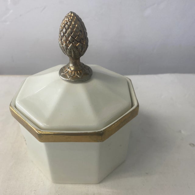 Adorable ceramic box by modernist Ernest Sohn features a white ceramic design with gold leaf and crest. Signed on back.