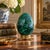 A beautifully proportioned malachite egg in richly veined shades of green and black resting on a neoclassical style brass...