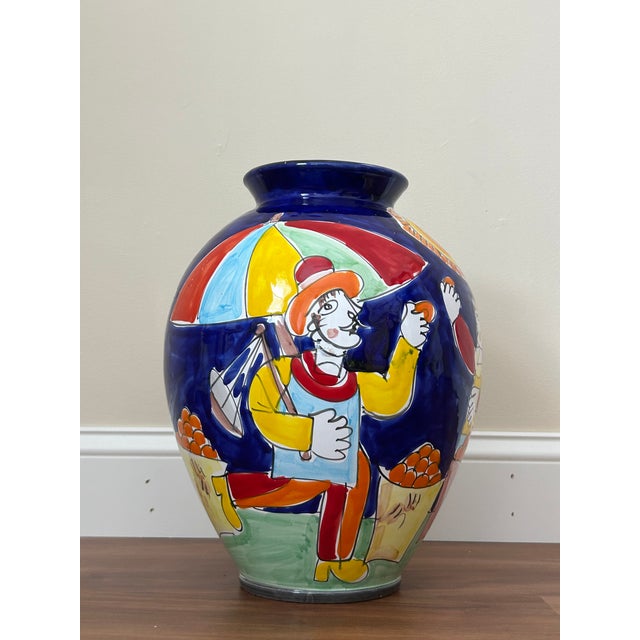 A vibrant vintage Italian ceramic floor vase by La Musa, featuring bold hand-painted folk art scenes in saturated cobalt...