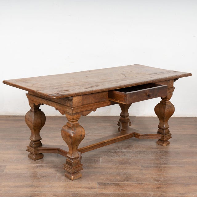 This handsome baroque oak library table with single functioning drawer has heavily turned legs and an attractive lower...