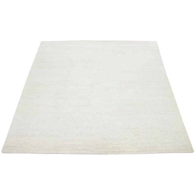 This hand-knotted Moroccan-style rug is made from wool and showcases a captivating minimalist aesthetic. It features a...