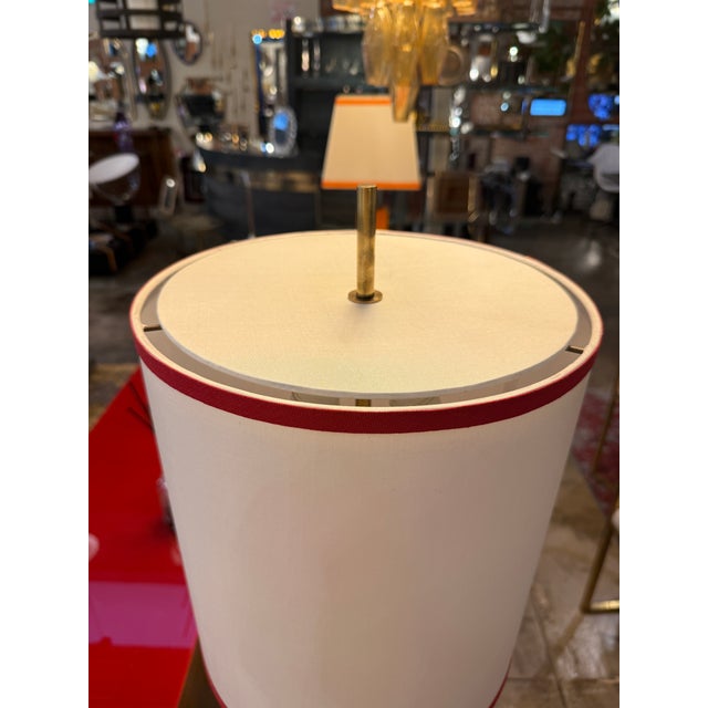 Refined 1950s Italian table lamp featuring a cylindrical column finished in glossy red lacquer, resting on a circular...