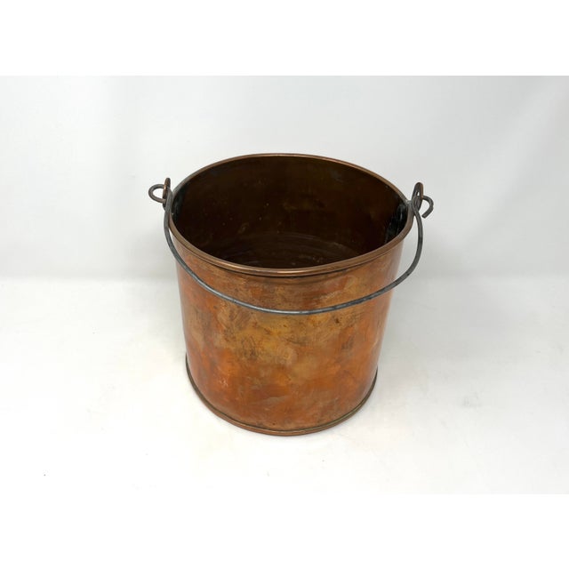 Late 19th century copper pot or bucket with rolled lip, iron handle, dovetailed seams at sides with brass solder and...