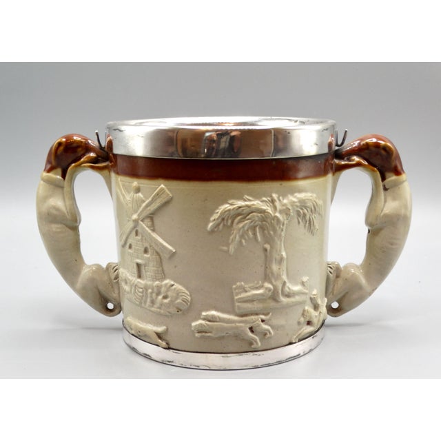Large antique English salt glazed hunting cup with handles in the form of whippet dogs. It has been embellished at the top...