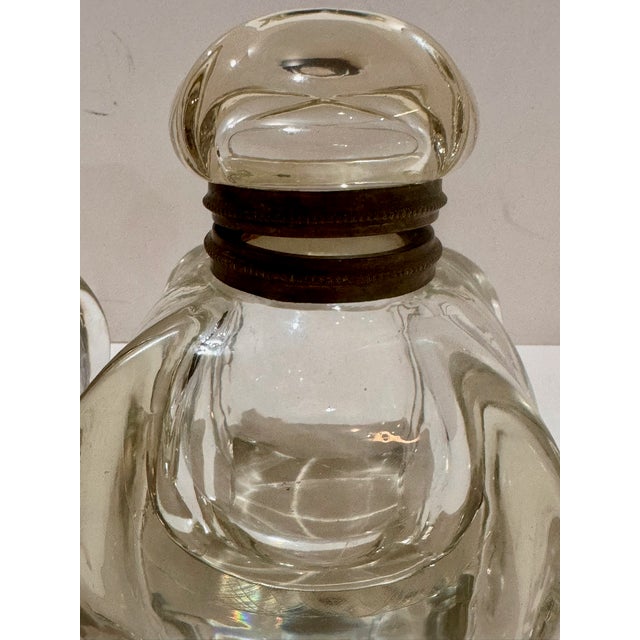 A matched pair of antique clear glass inkwells dating to the late 19th century. Hand-blown with thick glass walls. The...