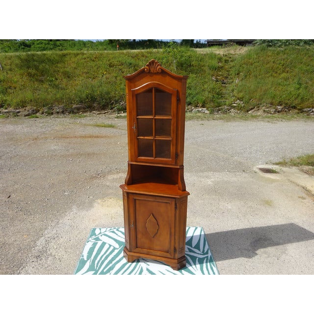 Small, tall, and narrow corner cabinet composed of two parts: a corner sideboard with one cupboard door topped by a...