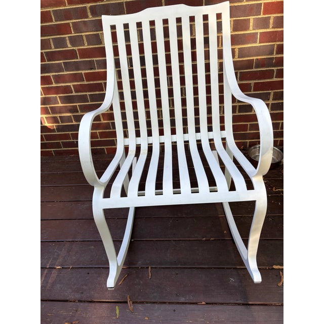 Aluminum Rocking chair of neoclassical inspiration, with curved back slats continuing to form the seat, open arms and...