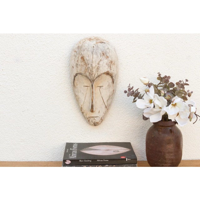 Discover the captivating allure of authentic African art with this vintage hand-carved wooden mask. Imbued with a rich...