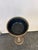 This vintage brass standing ashtray features a tapered column stem and a round base, displaying a natural green patina...