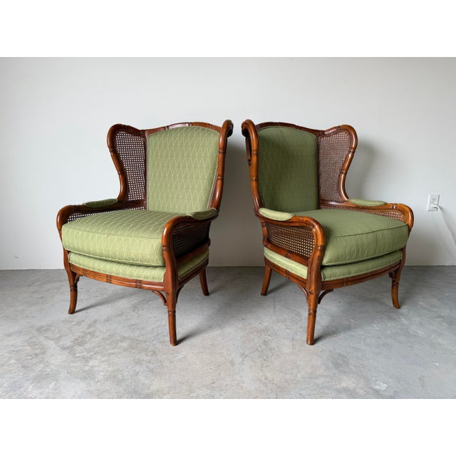 Elegant pair of vintage Ethan Allen wingback Bergère lounge chairs featuring carved faux bamboo frames, woven cane panels,...
