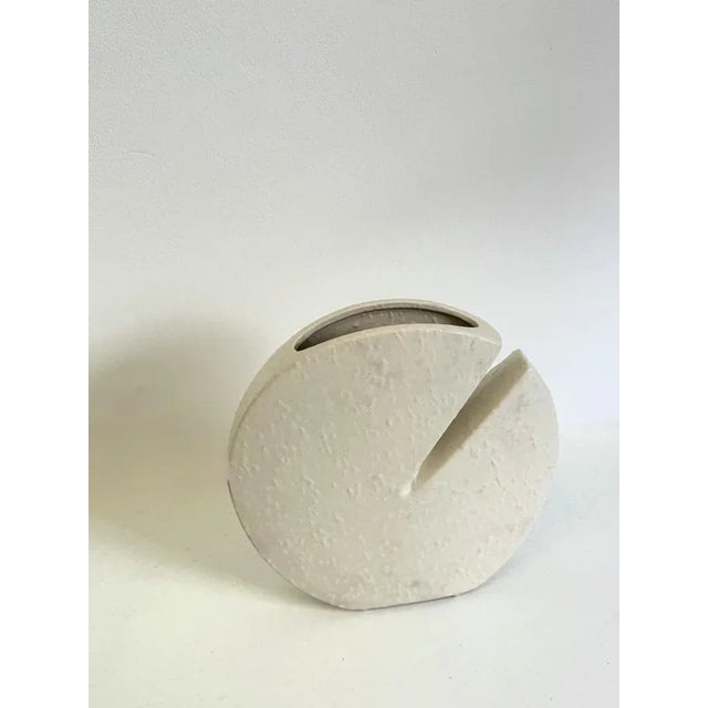 This off-white ceramic vase from 1972 is a creation by Nereo Boaretto. Its lenticular shape and narrow opening are...
