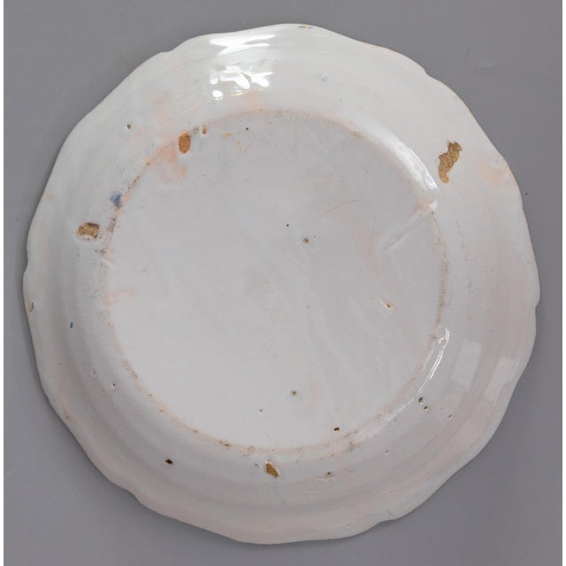 A wonderful 18th century Nevers polychrome plate feauturing a bird perched on top of of a spray of flowers emerging from a...