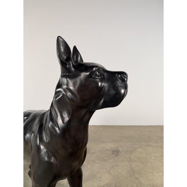 A striking life-size bronze sculpture of a Boxer dog, rendered in a refined and stylized interpretation. This piece leans...