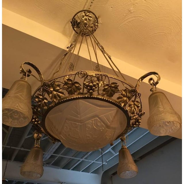 This French Art deco Chandelier has grapes and leafs motif surrounding the outer bowl on the metal work, with four tulips...