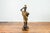 A vintage bronze candleholder statue with black and gold patina, on shell base. Created during the 20th century with the...