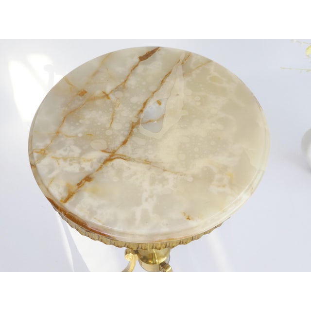 An elegant antique onyx and brass table. This charming Italian side table has a round onyx top with a brass ornate frame...