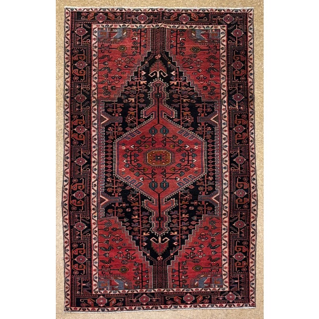 Antique hand-knotted rug from the Tuiserkan region of western Iran, featuring a bold elongated medallion design set on a...