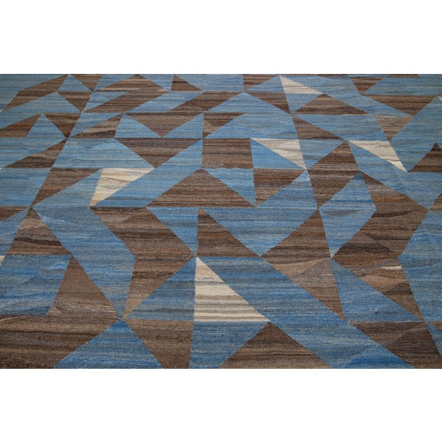 This Deco flatweave wool rug exhibits a captivating blue field with brown and beige accents, creating a contemporary and...