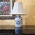 This charming vintage Chinoiserie-style table lamp features a glazed blue and white porcelain base decorated with the...