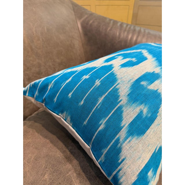 Woven on a traditional loom in pure silk, this lumbar cover carries an ikat pattern in bright sky blue against a white...