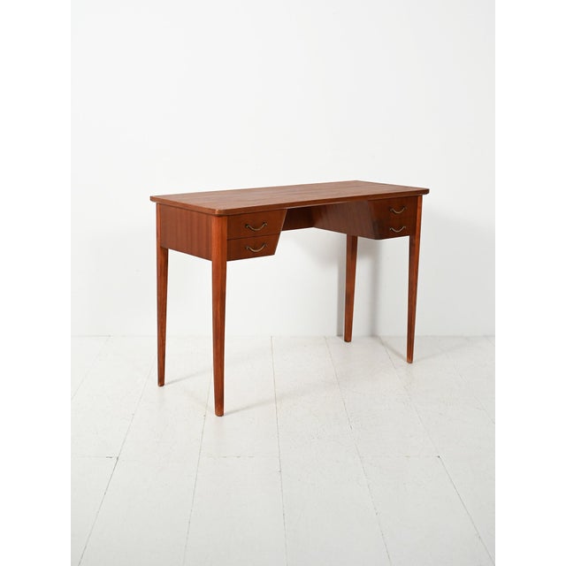 Elegant Scandinavian mahogany desk from the 1940s and 1950s with four drawers and brass handles, featuring a light and...