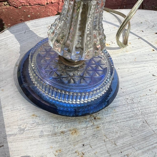 This vintage glass table lamp combines clear and cobalt hues with elegant brass accents. Its textured base and compact...