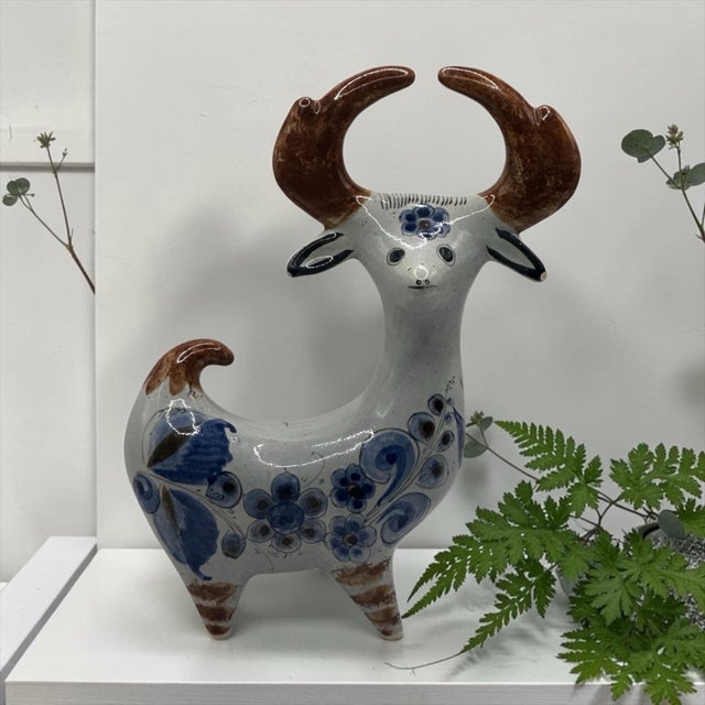 This ceramic figurine represents the rich tradition of Mexican folk pottery. The blue floral motifs and hand-painted...