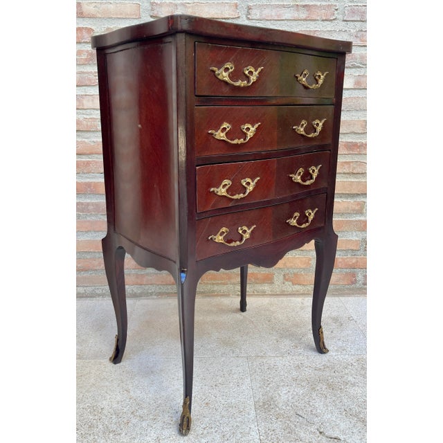 Beautiful wooden side table from the 40s. It has four drawers with bronze handles and is supported on four stylized, well-...