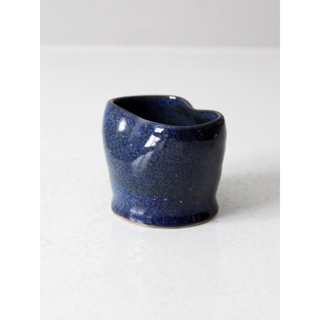 This vintage studio pottery vase features a deep blue, speckled glaze and a unique, hand-shaped form. It showcases the...