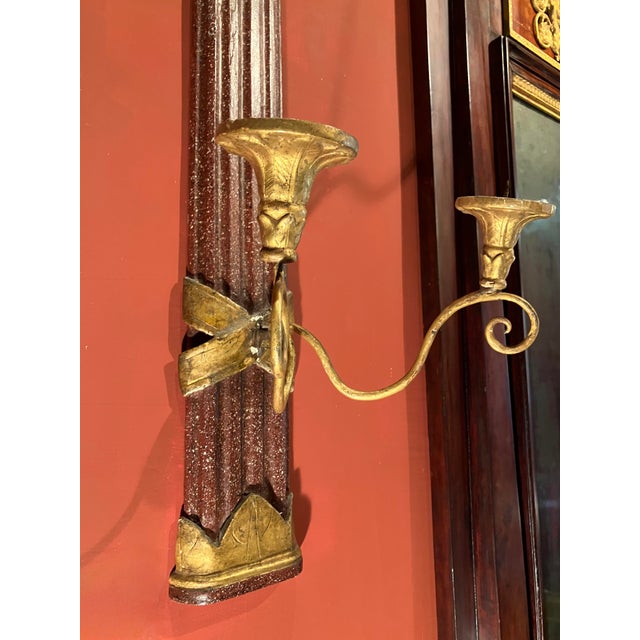 A rare pair of antique Tuscan Empire giltwood and faux porphyry wall sconces from a historic Italian villa, masterfully...