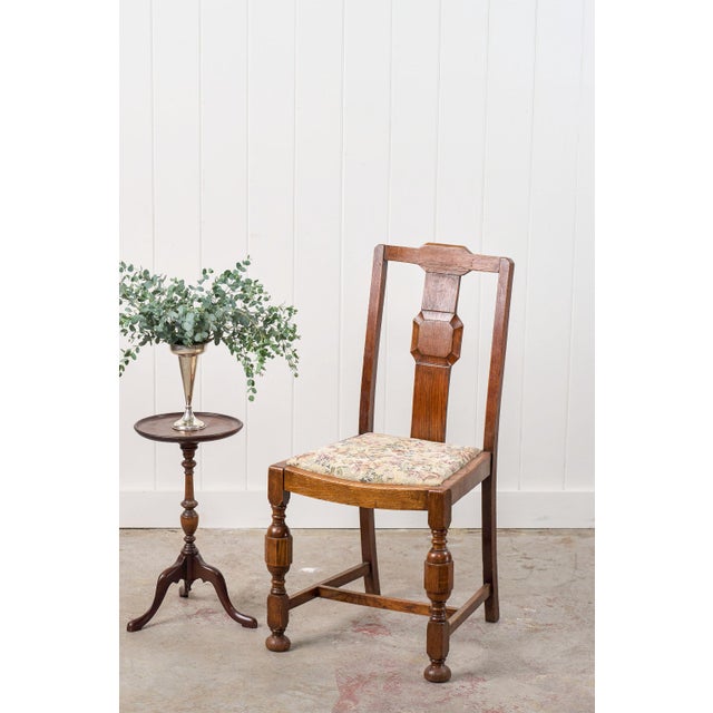 This antique English oak carved back chair features a geometric backrest design with beveled accents and a classic floral...
