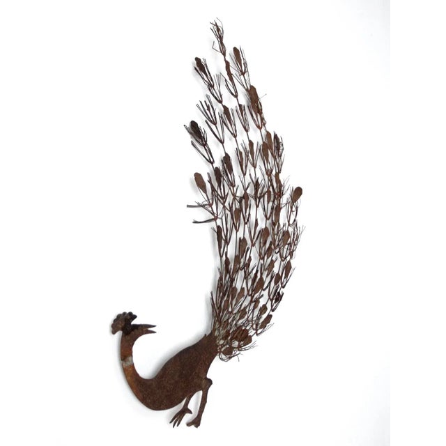 This is a vintage metal peacock wall hanging. The intricately "feathered" bird art makes a bold statement.