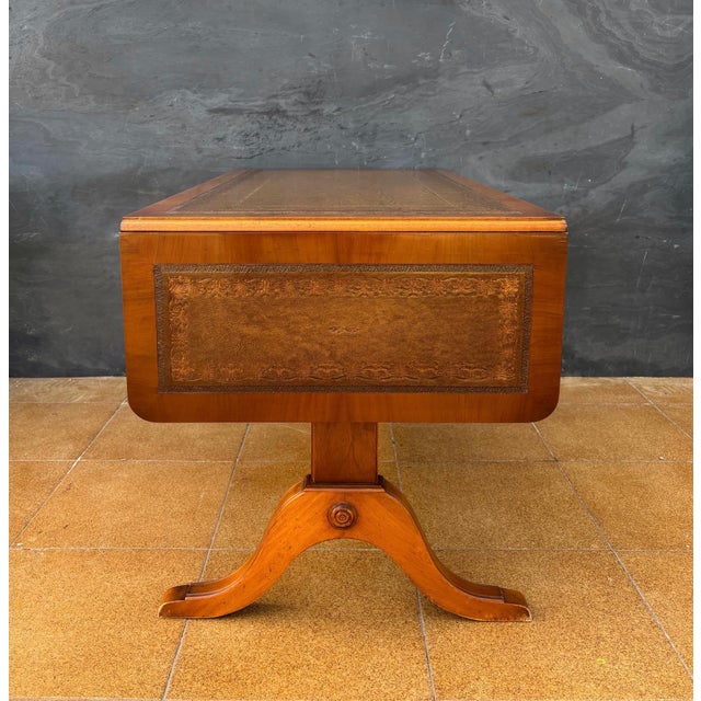 Elegant drop-leaf low table dating to the mid-20th century. The table features a rectangular top with a leather writing...