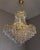 An exceptional and highly decorative monumental crystal chandelier, executed in the glamorous Hollywood Regency style and...