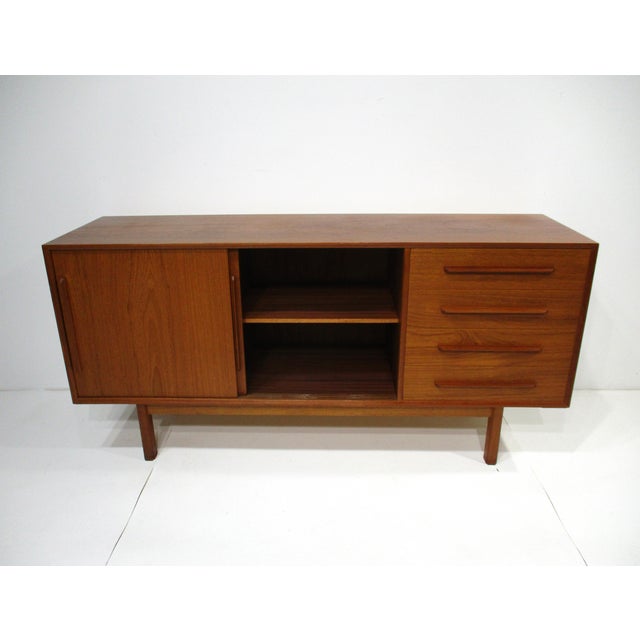 A teak wood two sliding door credenza with adjustable shelves and four drawers to the right side making for perfect...