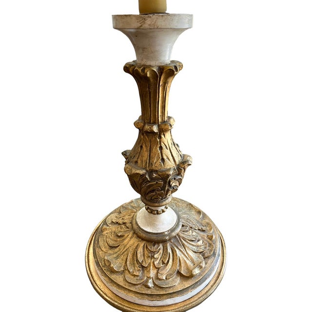 The base of this candlestick lamp is painted cream and gold. It is wired for modern use and includes a cream shade.