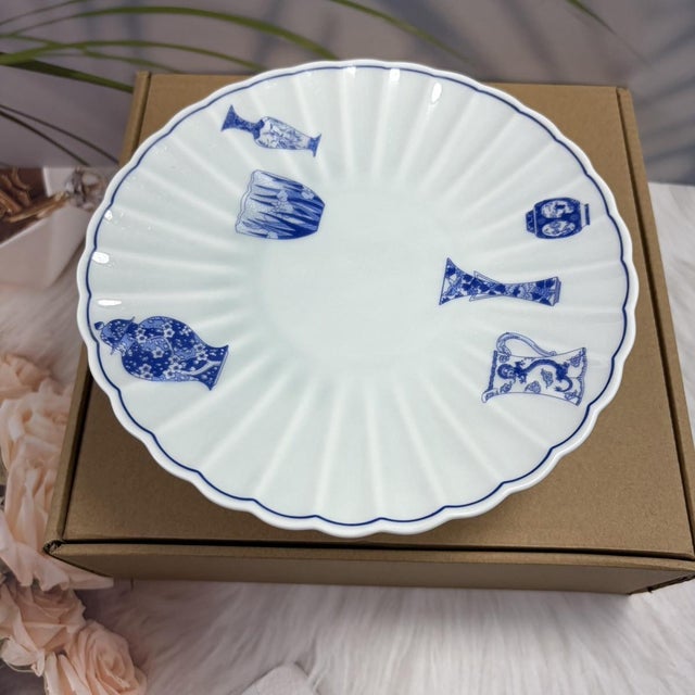 A Japanese-made blue-and-white porcelain dish on a pedestal, shaped like a chrysanthemum petal and decorated on the inside...