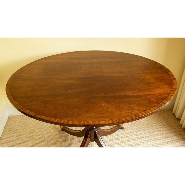 Beautiful 19th Century English Regency Mahogany Table. Table features an oval mahogany top enriched by a carved and banded...