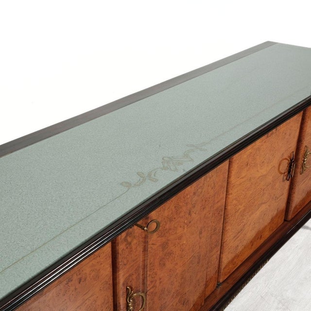 Elegant and original wooden sideboard with glass shelf in shades of light green, finely decorated. The sideboard is made...