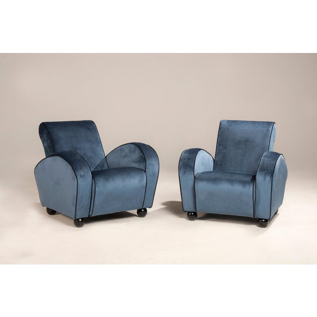 Pair of art deco armchairs in blue velvet with black borders. The armchairs have been reupholstered with hand-tailored...