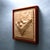 This artwork features a meticulously carved depiction of a pair of shoes, rendered in warm tones of maple and padauk. The...