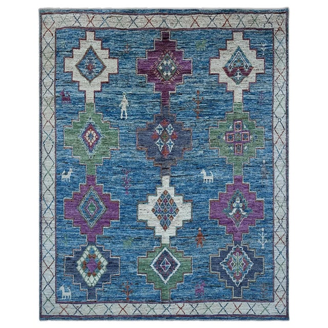 A vivid blue tribal area rug, where twelve stepped medallions in orchid, ivory, sage green and slate violet stack in three...