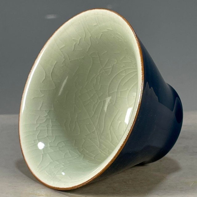 This is an elegant vintage porcelain teacup, featuring a striking monochrome glazed exterior and a contrasting celadon...