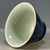 This is an elegant vintage porcelain teacup, featuring a striking monochrome glazed exterior and a contrasting celadon...