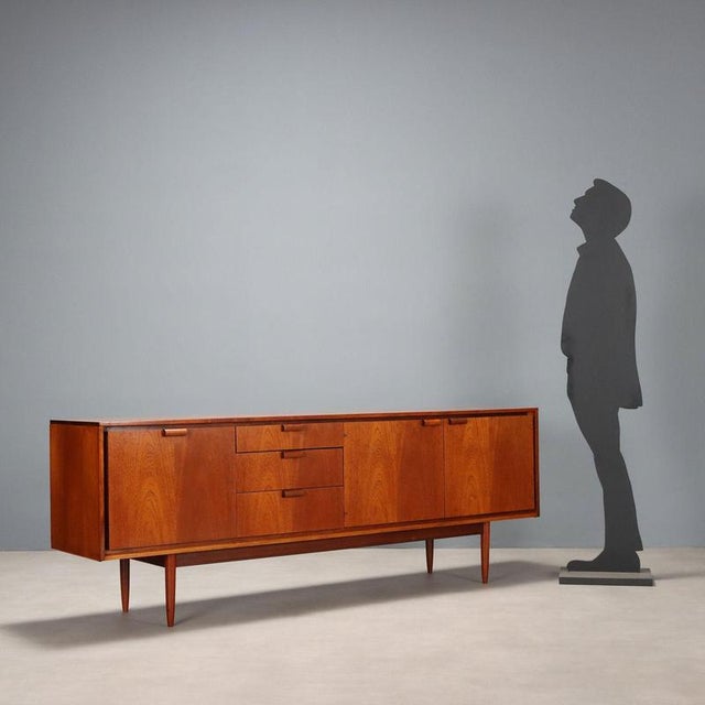 Vintage teak veneered sideboard with drop-down door for a bar area, pair of hinged doors, and open drawers. Restored in...